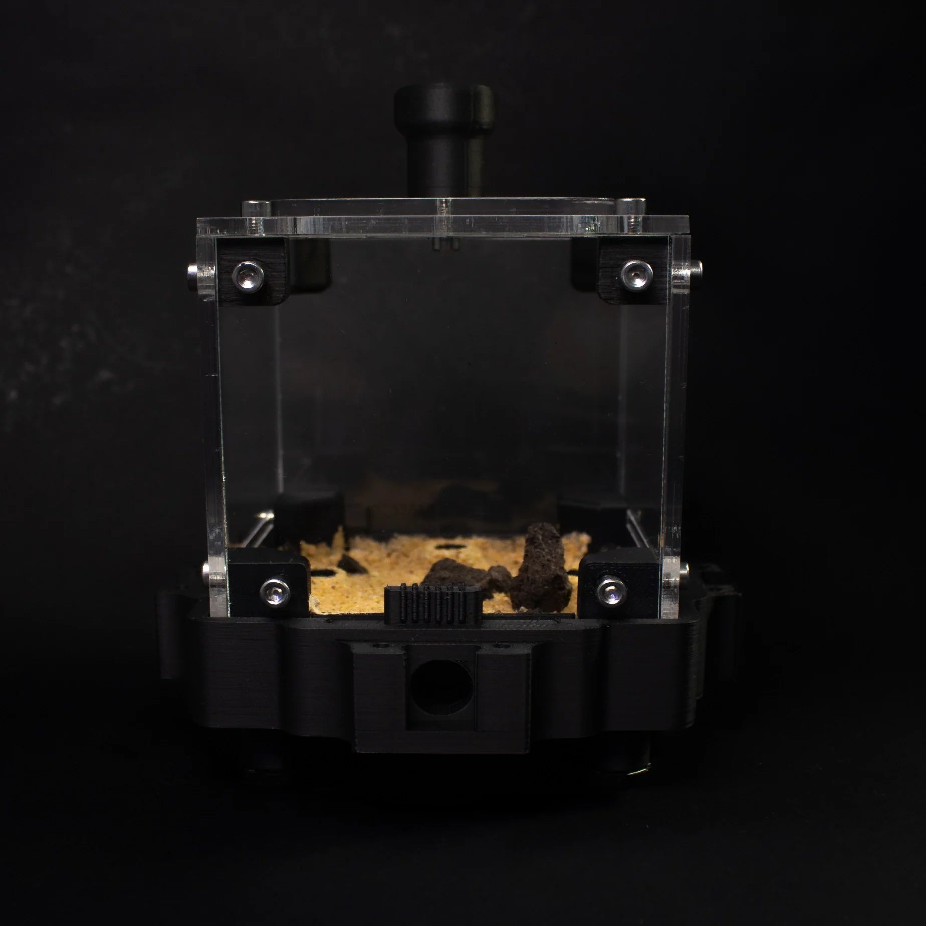 Transparent habitat box for terrarium with sand and rocks, showcasing a decorative display for plants or small animals.